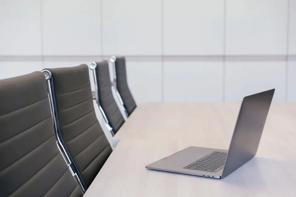 Silver Laptop on Wooden Table with Office Chairs